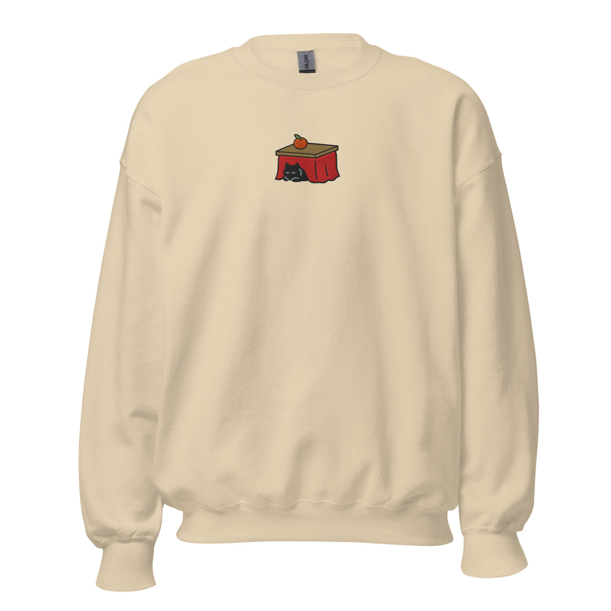 Sand crewneck sweatshirt with an embroidered black cat sleeping under a red Japanese kotatsu table with a mandarin orange on top