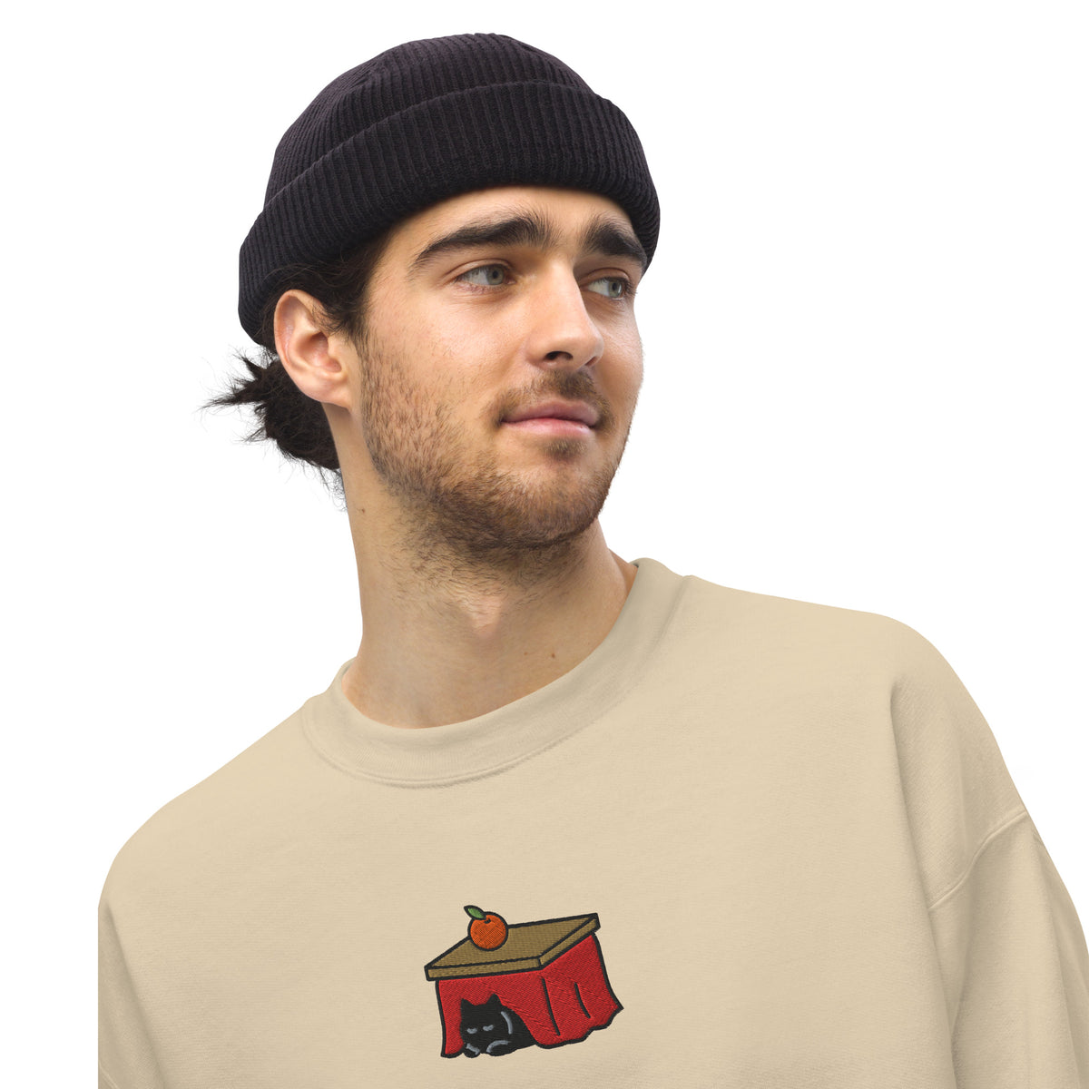 Close-up of the embroidered Kotatsu Cat on the chest of a sand sweatshirt worn by a model
